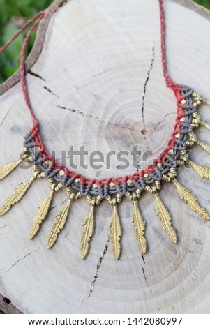 Macrame summer jewelry with brass metal components on wooden background