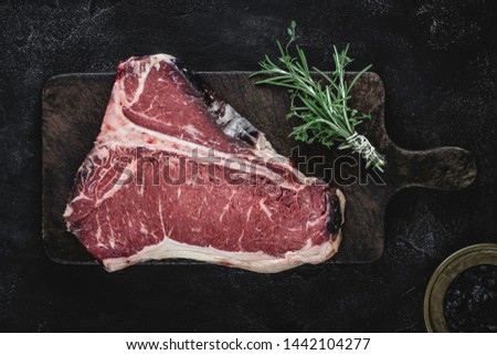 Prime Dry Aged Beef Raw T-bone Steak on Vintage Cutting Board Royalty-Free Stock Photo #1442104277