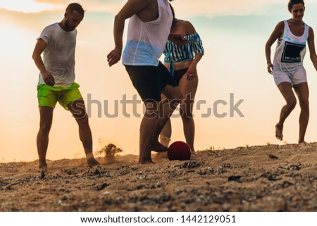 Group of young people playing soccer and competing together on a sandy beach