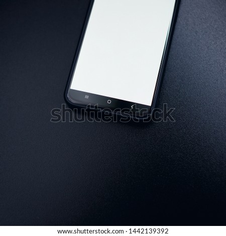 Modern black smart phone isolated on dark background in perspective view. New smartphone mockup with blank touch screen.