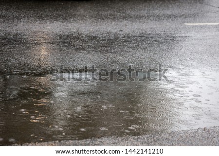 puddle on asphalt road at rain in city with selective focus and boke blur