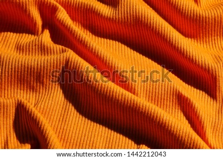 Background of crumpled orange fabric texture closeup.