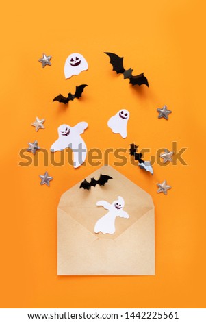 Halloween flat lay composition of raft paper envelope and black paper bats fly up on an orange background, top view.