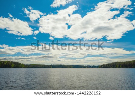 Lake, clouds and sky landscape. Forest on background. Finland