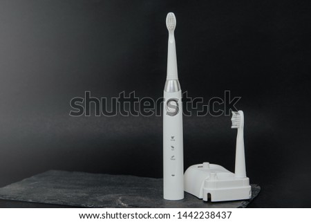 White sonic toothbrush on a dark stone background. Medical and dental concept. Caring for teeth, modern methods of removing calculus from teeth. Electric toothbrush.