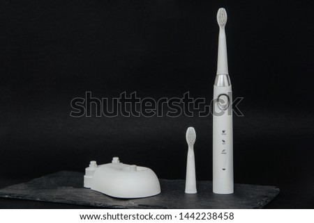 White sonic toothbrush on a dark stone background. Medical and dental concept. Caring for teeth, modern methods of removing calculus from teeth. Electric toothbrush.