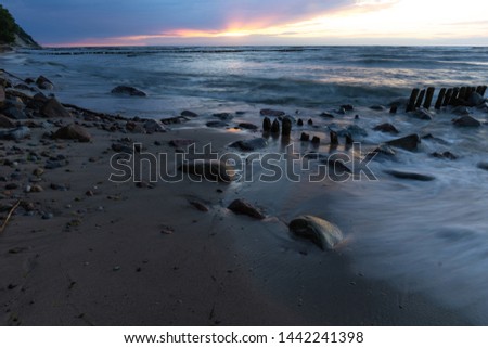baltic sea with old breakwaters at long shutter speed at sunset