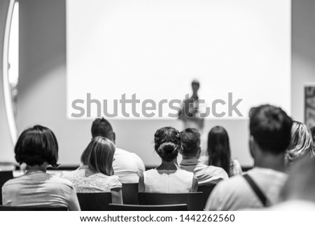 Speaker giving talk at business event. Audience at the conference hall. Business and Entrepreneurship concept. Focus on unrecognizable people in audience. Black and white photo.