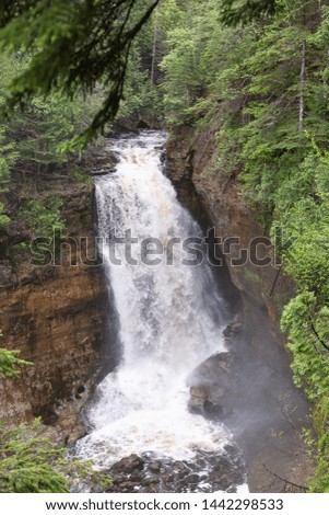 Miner's Falls waterfall at Pictured Rocks National Lakeshore-Water rushing over rocks and cascading down rock formation surrounded by trees