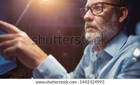 Businessman with glasses working focused in office at night, authentic wide angle shot