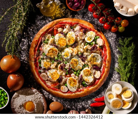 Traditional Portuguese Pizza with egg, olive, palm heart and pea. Top view on black concrete background, close up. Traditional Brazilian Pizza
