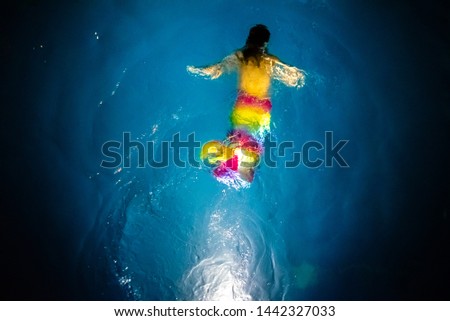 Silhouette of a mermaid girl diving in the calm waters of a deep chasm, background of fantasy tales and marine children's dreams.