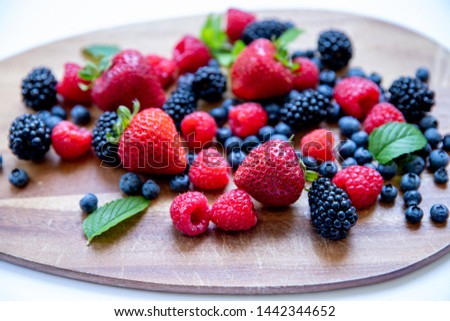 Strawberry, blueberry, raspberry variety on wooden and white background