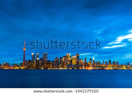 TORONTO CITY SKYLINE AT NIGHT - Beautiful blue evening scene of Toronto cityscape with glowing city lights inside buildings. Wide shot with blue, orange and yellow colors. Toronto, Ontario, Canada