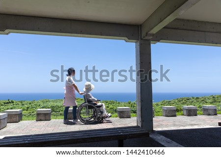 Senior and care helper taking a walk with a wheelchair