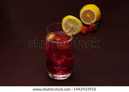Drink with ice from strawberries on a dark background. Fresh strawberry cocktail. Fresh summer cocktail with strawberry and ice cubes. Glass of strawberry soda drink on dark background.