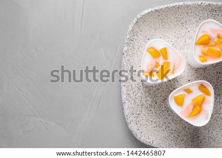 Plate with cups of peach yogurt on table, top view. Multi cooker recipe. Space for text