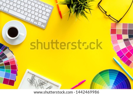 Work space of designer with instruments, pallet, keyboard, glasses and coffee yellow background top view space for text