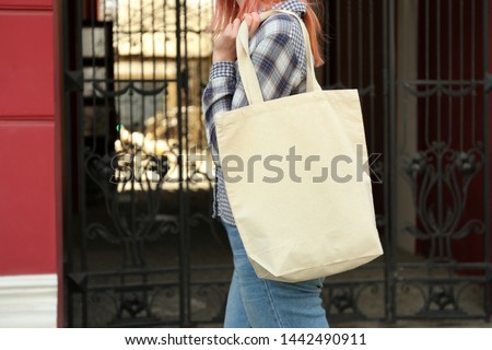 Young woman with cotton bag on city street, closeup. Mockup for design