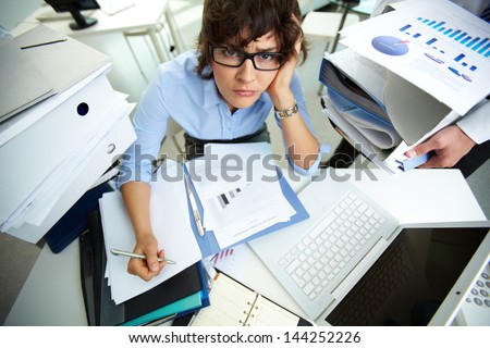 Perplexed accountant doing financial reports being surrounded by huge piles of documents Royalty-Free Stock Photo #144252226