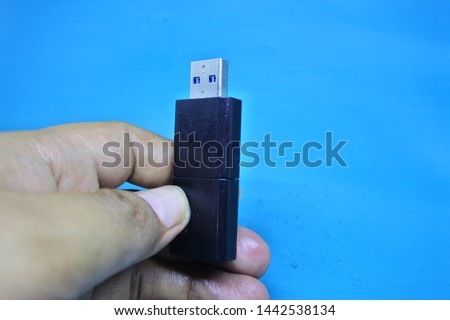 hands hold the black flashdisk on blue background