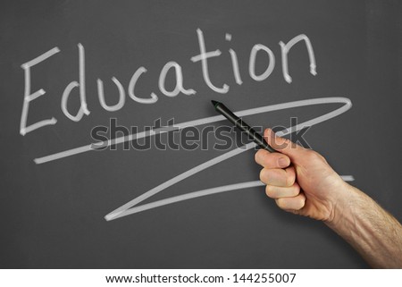 Mans hand pointing to a education message on a chalkboard.