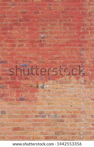 Old deteriorating clay brick wall background texture with areas of worn and peeling red paint