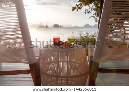 Breakfast in a Beautiful location with Sea and Mountain View. Beach chairs and table with fresh tropical fruits, coconut and red watermelon shake cocktail. Green grass and amazing sea view background