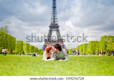 Loving couple lying on the grass on the Champ de Mars in Paris with the Eiffel Tower in the Background