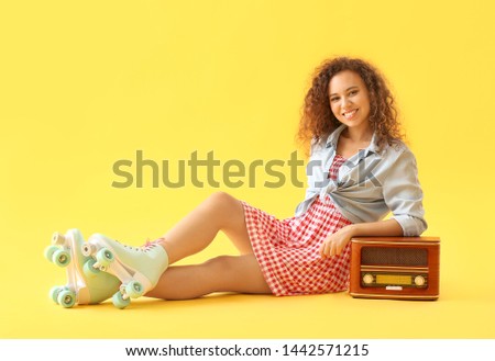 Beautiful young woman on roller skates and with retro radio receiver against color background