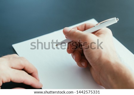 Business correspondence. Closeup of man hand holding pen over blank sheet of paper. Copy space.
