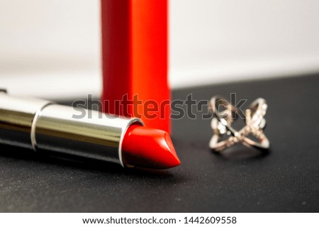 A red lipstick and a silver ring on the black and white background. Close up photo.