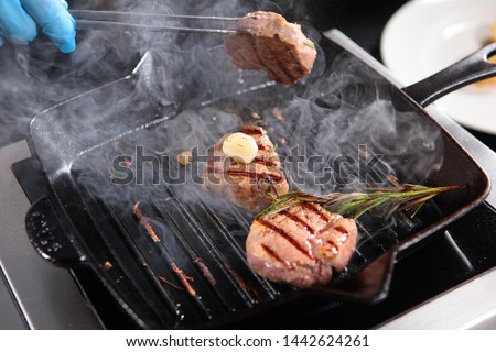 Cooking a piece of beef on the grill indoors. Cooks hands in the frame. Fillet of beef minion. Thin part of the tenderloin. Delicious dish of natural meat.The concept of cooking in the restaurant.