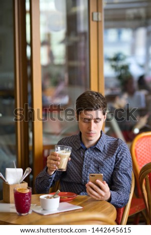 man in cafe sitting with coffee and smartphone