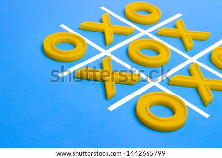 Yellow plastic crosses and a toe and a ruled field for playing tic-tac-toe on a blue background. Concept XO Win Challenge. Educational game for kids