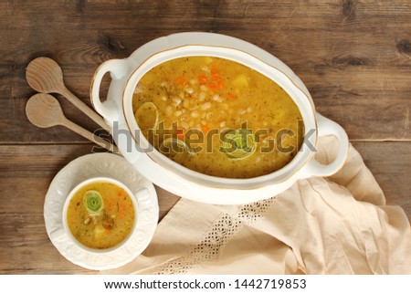 fresh hot bean soup in a white plate and white tureen on an old wooden table Royalty-Free Stock Photo #1442719853