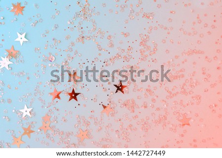 Delicate glitter star confetti on coral and blue background. Creative and moody color of the picture.