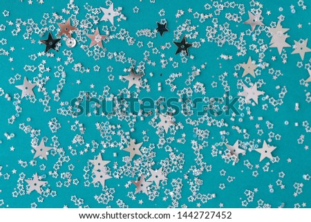 Delicate glitter star confetti on turquoise background. Creative and moody color of the picture.