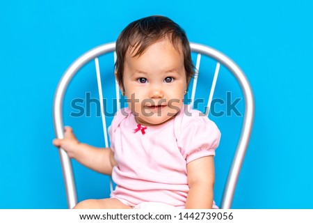 small baby girl with dark hair and brown eyes mixed rase, kazakh girl and russian on blue background.