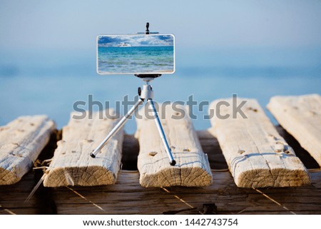 Smartphone on tripod making photo and video of sea landscape