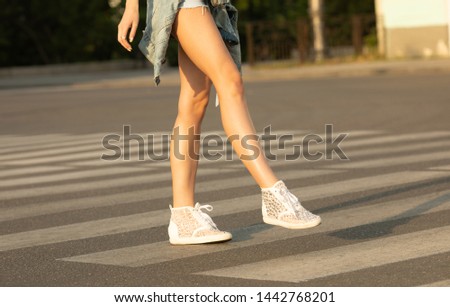 Close up of woman legs walking on crosswalk. Young woman crossing the street.