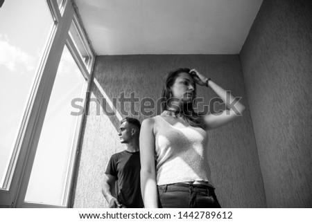 Black and white picture of couple in light room with large windows. Young man with his girlfriend. Young woman with her boyfriend. Couple in love.