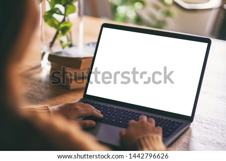 Mockup image of a woman using and typing on laptop with blank white desktop screen on wooden table Royalty-Free Stock Photo #1442796626
