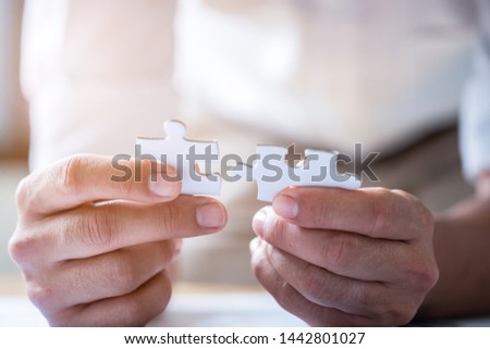 Hands connecting jigsaw puzzle. Business solutions, success and strategy concept. Close up photo with selective focus.
