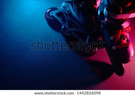Close up view of roller skates inline skate or rollerblading on dark grunge background in neon blue magenta pink light