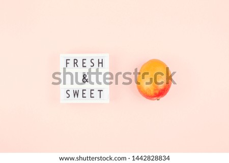 Mango fruit in creative conceptual top view flat lay composition with lightbox with Fresh and sweet text isolated on pink background in minimal style with copy space. Pop art concept poster