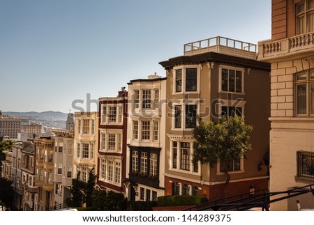 Descending row of stately houses on hill in San Francisco Royalty-Free Stock Photo #144289375