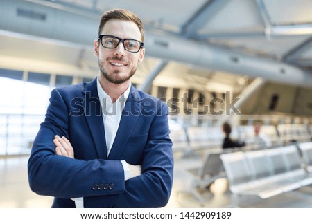 Confident man as successful manager with crossed arms in airport terminal