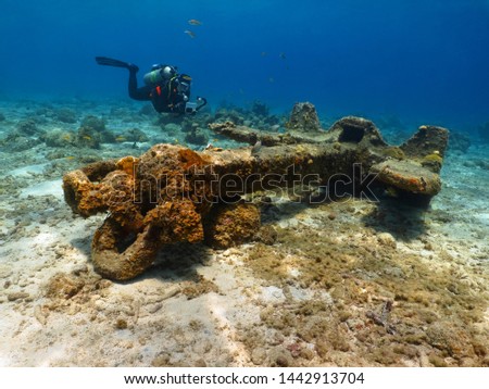 Scuba diver and huge anchor. Underwater photographer posing with rusty anchor, photography from scuba diving in the ocean. Sea exploration, landscape with tourist and metal structure in the harbor.
