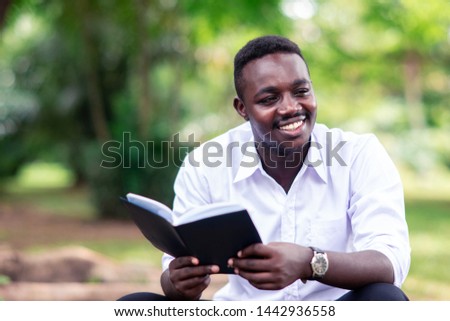 African man reading a book in the park